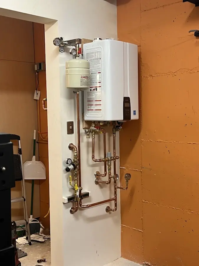 Plumbing technician inspecting water heater connections in Lindenhurst
